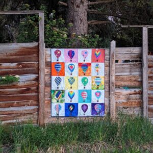 Quilt hanging on a wooden fence using the Rise Above quilt blocks